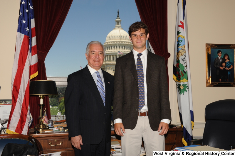 Congressman Rahall stands in his Washington office with a young man wearing a brown blazer and blue patterned tie.