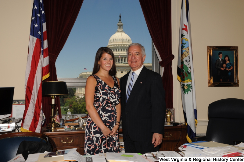 Congressman Rahall stands in his Washington office with a young woman wearing a ribbon-patterned dress.