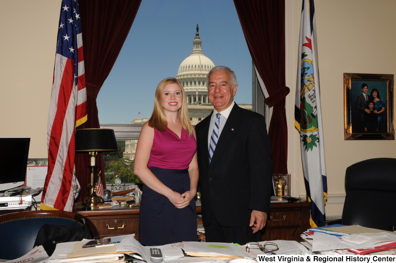 Congressman Rahall stands in his Washington office with a young woman wearing a magenta top.