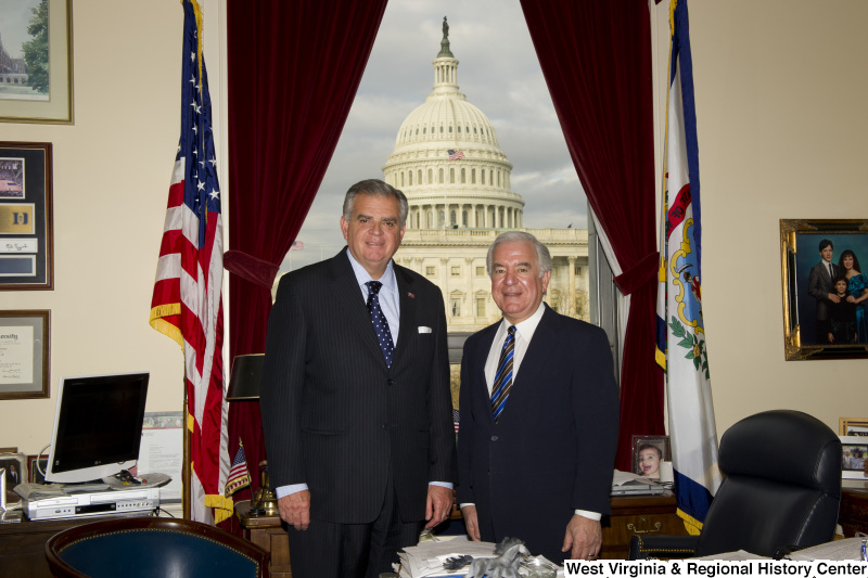 Congressman Rahall stands in his Washington office with a man wearing a dark pinstripe suit and blue and white spotted tie.