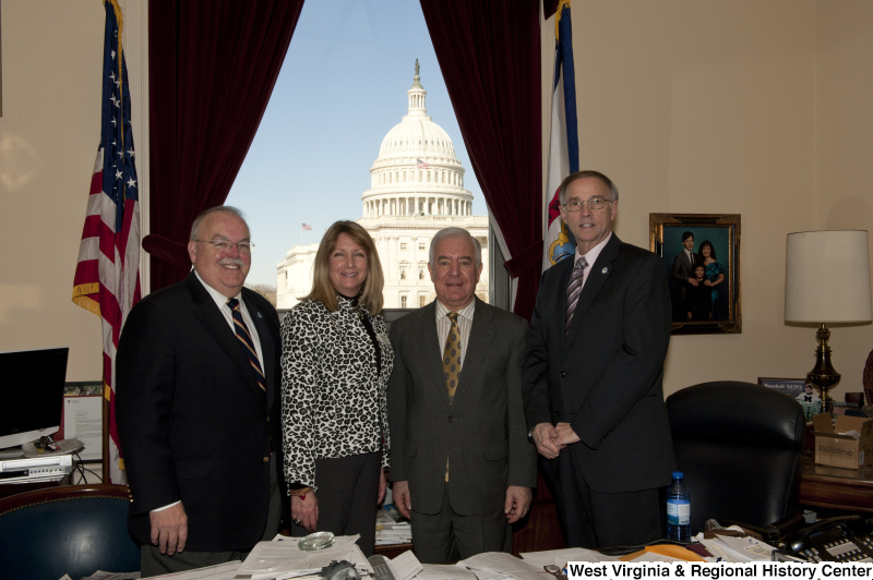 Congressman Rahall stands in his Washington office with two men and a woman, who wears a leopard-print jacket.