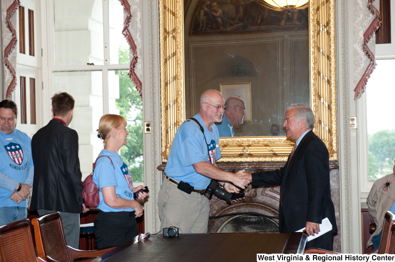 Congressman Rahall shakes hands with people wearing "Honor Flight" shirts at a military award ceremony.