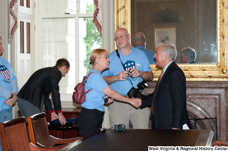 Congressman Rahall shakes hands with men and women wearing "Honor Flight" shirts at a military award ceremony.