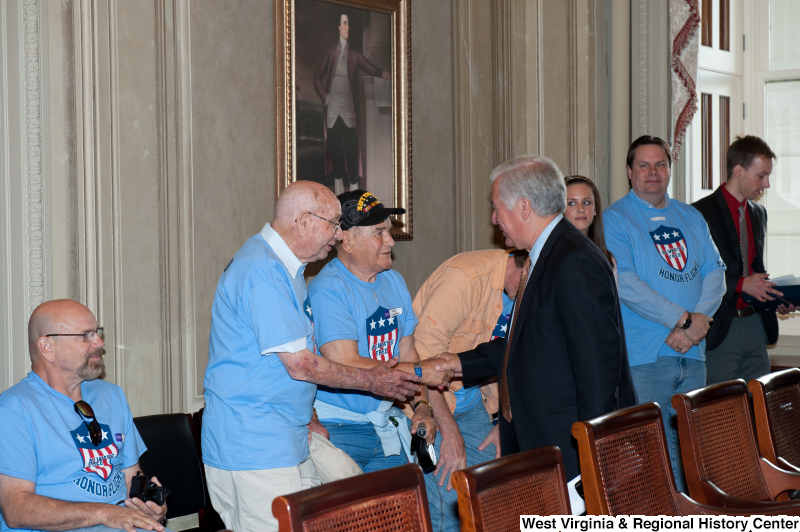 Congressman Rahall shakes hands with men wearing "Honor Flight" shirts at a military award ceremony.