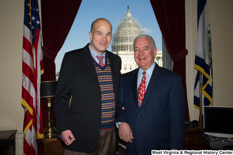 Congressman Rahall stands in his Washington office with a man wearing a dark blazer and multicolored sweater.