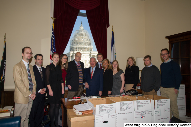 Congressman Rahall stands in his Washington office with a group of people behind archival storage boxes.