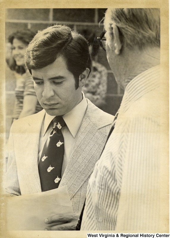 Congressman Nick Rahall II while listening to an unidentified man. Rahall is wearing a West Virginia tie.