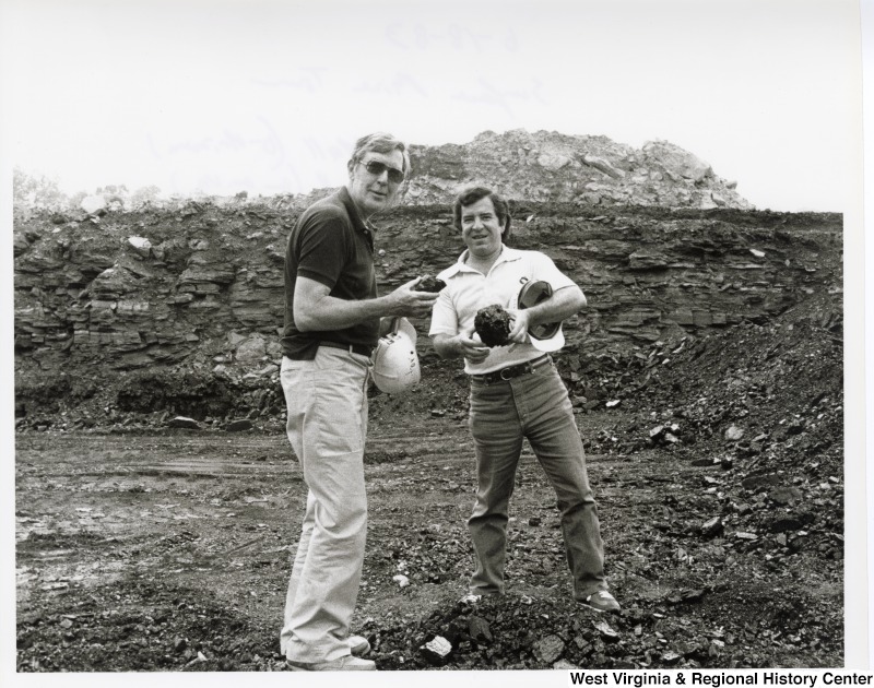 Congressman Nick Rahall II and Congressman Mo Udall (AZ) at a surface mine (strip mining) tour. They are holding what appears to be coal.