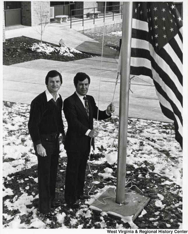 Congressman Nick Rahall II and Bob Bowlin, of the Beckley YMCA, raising the American flag. The flag was potentially gifted by Rahall.