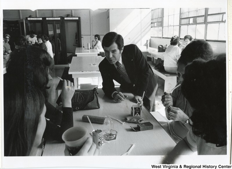 Congressman Nick Rahall II leaning over a table talking to a group of unidentified women during a campaign trip.