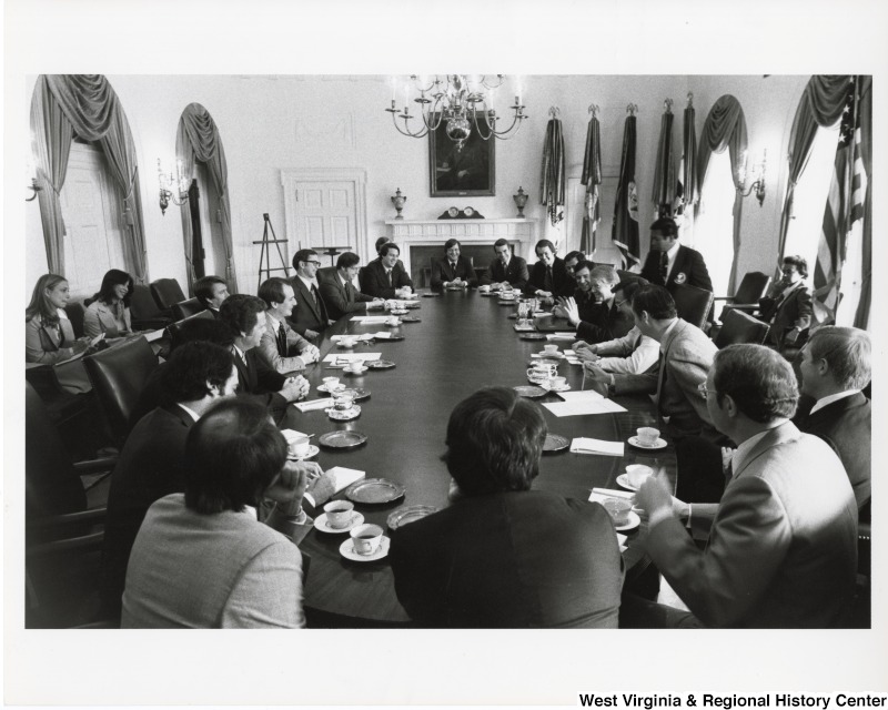 President Jimmy Carter talking with a group of men in a boardroom. Congressman Nick Rahall II is sitting to the right of President Carter.