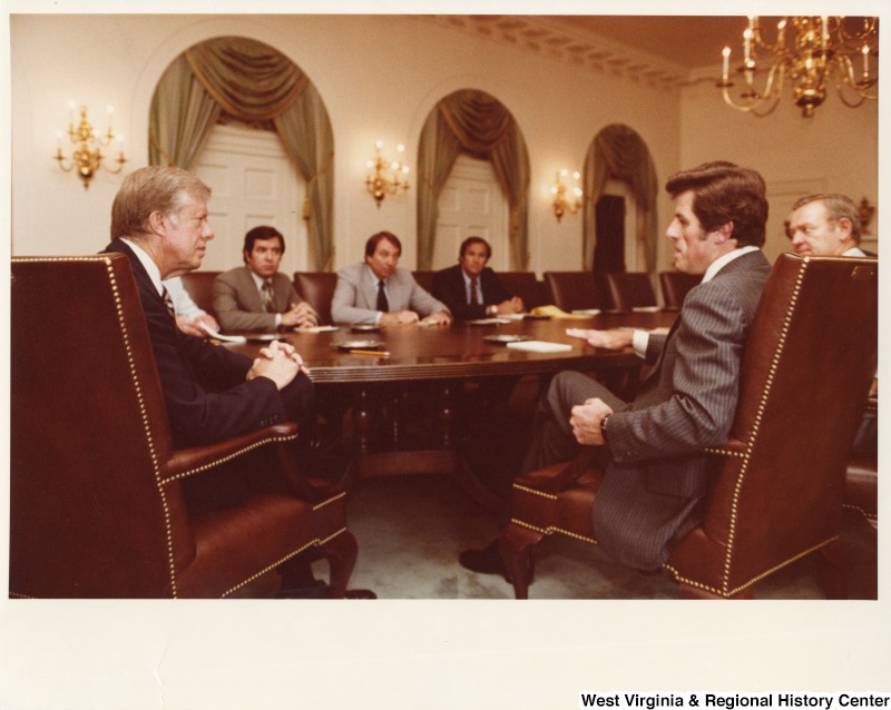 President Jimmy Carter talking with Congressman Harley Staggers (D-WV) (hidden), Congressman Nick Rahall II (D-WV), Frank Moore a White House aide, Congressman Jim Broyhill (R-NC), and Congressman Jim Florio (D-NJ) about railroad deregulation.