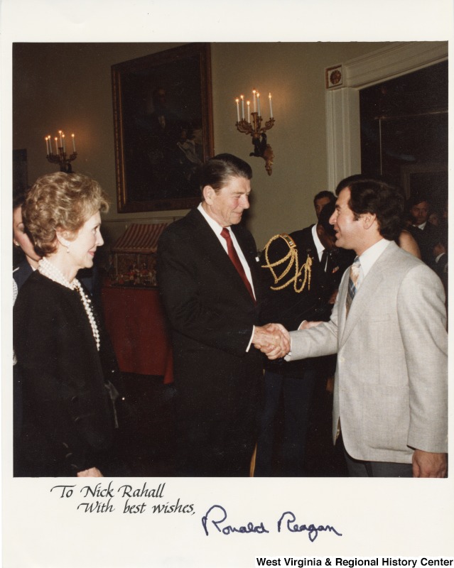 Congressman Nick Rahall II shaking the hand of President Ronal Reagan. Nancy Reagan is standing beside of them. The photograph is signed "To Nick Rahall with best wishes, Ronald Raegan."