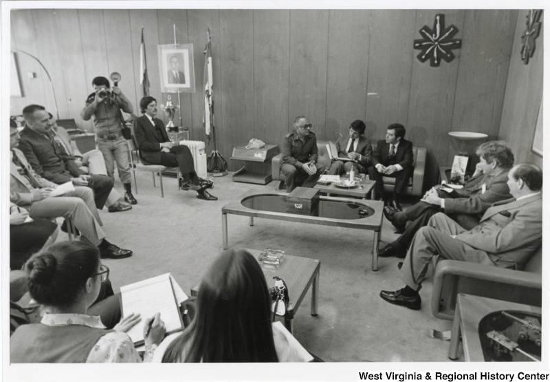 From left to right: Congressman Bob Carr, General Khoury, Congressman Toby Moffett, Congressman Nick Rahall, and Congressman Pete McCloskey (on the couch to the far right). The Congressmen and General are discussing America's support for the Lebanese Army. They are in General Khousy's office. There are other unidentified people in the room with them, as well as a photographer.