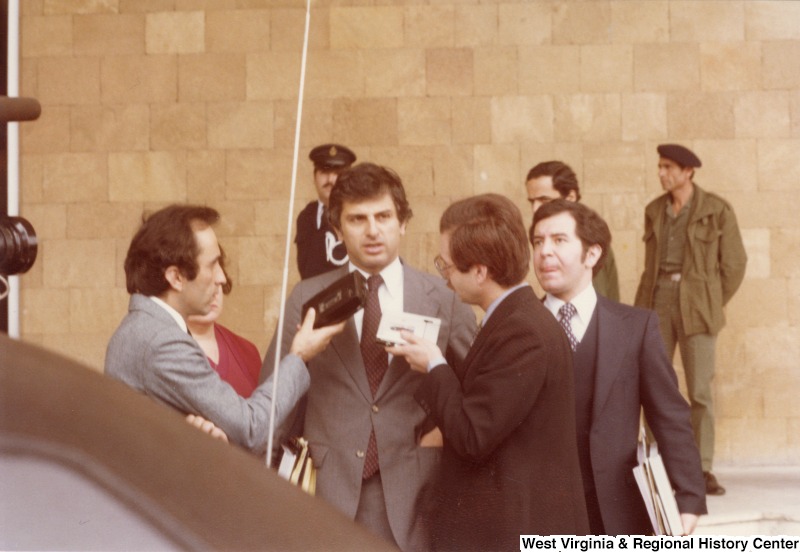 Congressman Toby Moffett speaking to two unidentified people of the press. Congresswoman Mary Rose Oakar is standing to his right and Congressman Nick Rahall is to his left.