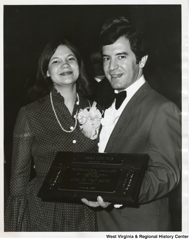 Congressman Nick Rahall II and his first wife, Helen, showing an award Rahall received from the Amara Civic Club. The plaque reads "Amara Civic Club presents to the Honorable Nick J. Rahall, II, M.C., Democrat, 4th Congressional District, West Virginia. Award for public service. Washington, D.C. April 2, 1977."