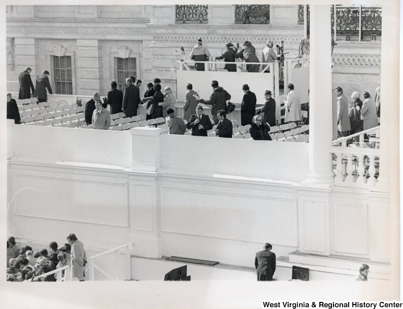 Congressman Nick Rahall II with two unidentified men looking over a balcony.