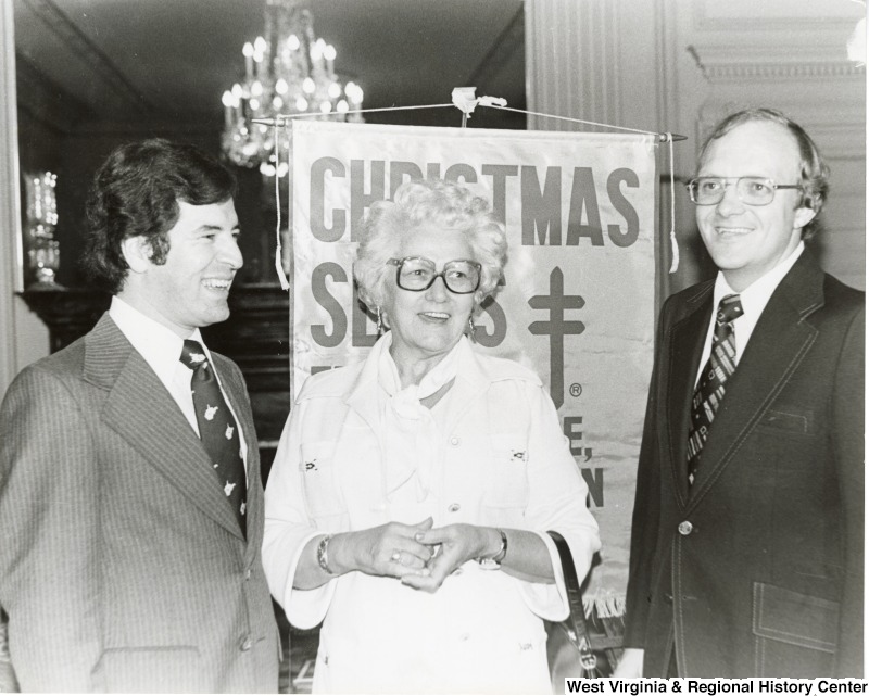 From left to right: Congressman Nick Rahall II, a unidentified woman, and Dick Calloway, WWNR, St. Albans? mayor. They are the Charleston Capitol building for the Christmas Seals.