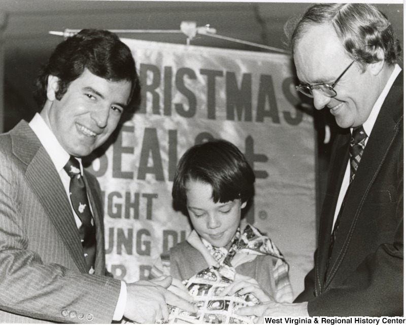 Congressman Nick Rahall II, a unidentified boy and Dick Calloway, WWNR; St. Albans(?) mayor at the Christmas Seals event at the Charleston Capitol Building.
