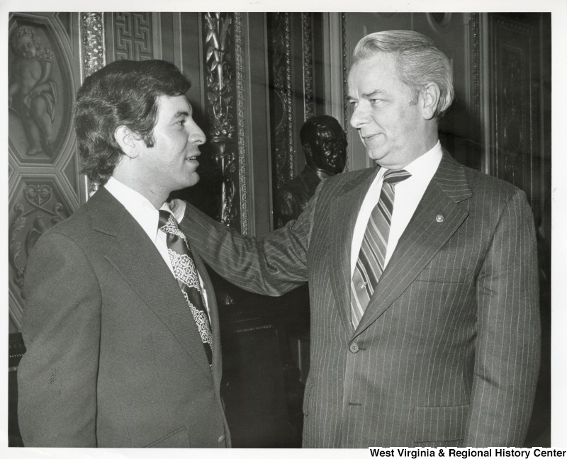 Congressman Nick Rahall II speaking to Senator Robert C. Byrd. Byrd has his hand on Rahall's shoulder. They are standing in the Senate Chambers right off the Senate floor.