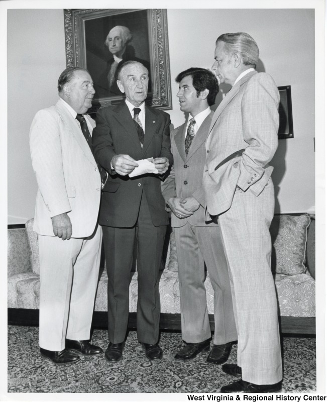 From left to right: Senator Jennings Randolph, Senate Majority Leader Mike Mansfield, Congressman Nick Rahall II, and Senator Robert C. Byrd standing in front of a couch talking.