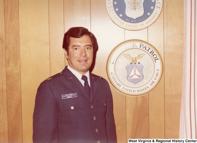 Congressman Nick Rahall II standing beside the insignia for the Civil Air Patrol, Axillary United States Air Force.
