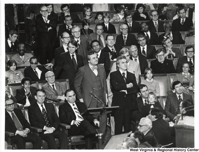 An unidentified group of adults and children seated in an auditorium.