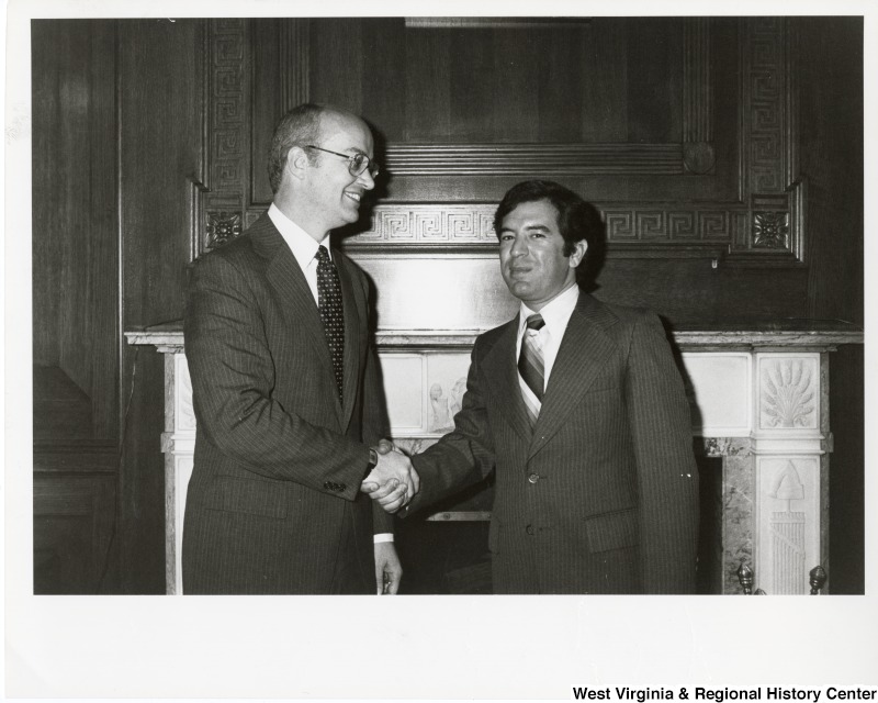Congressman Nick Rahall II shaking hands with an unidentified man.