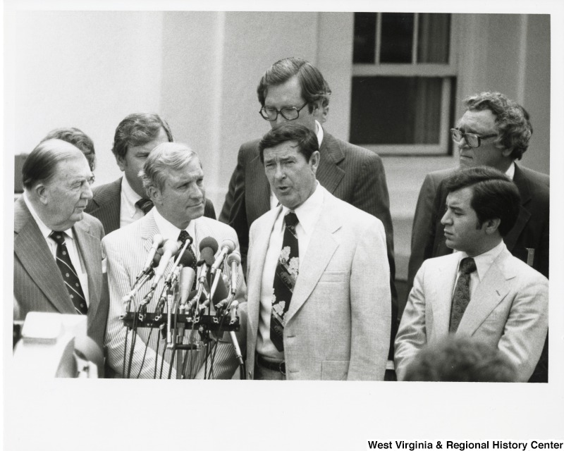 From left to right; Senator Jennings Randolph (D-WV); Congressman Walter Huddleston (D-KY) (back); Congressman Charles Percy (R-IL); Senator John Rockefeller (D-WV) (back); Congressman Austin Murphy (D-PA); and Congressman Nick Rahall (D-WV). Congressman Murphy is speaking about coal in front of a microphone.