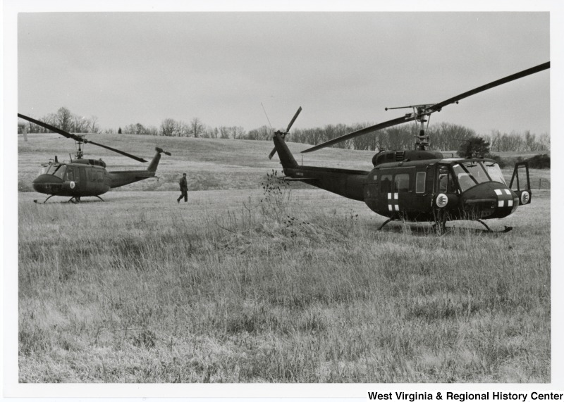 Two helicopters in an open field.