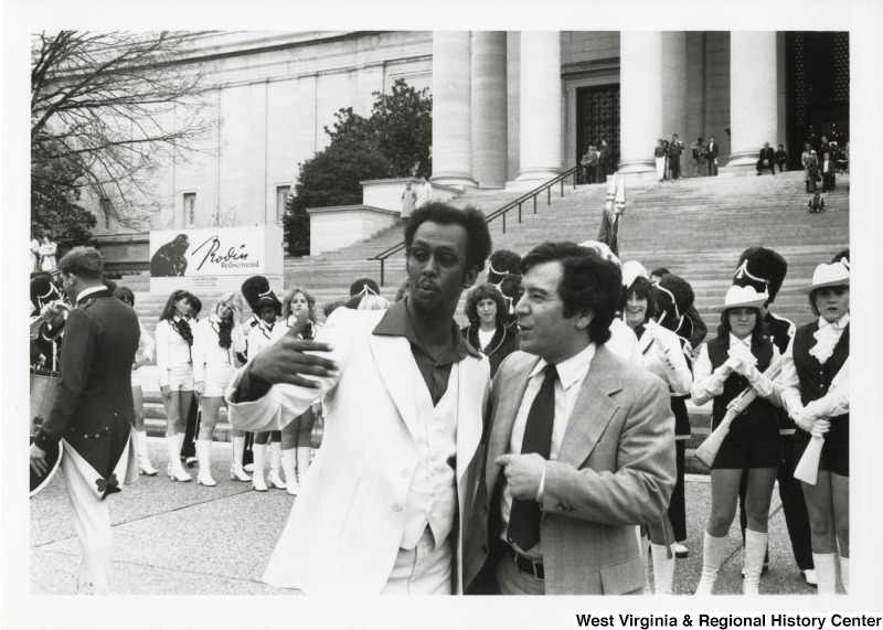 Congressman Nick Rahall with an unidentified man on the steps of the Capitol complex. There is a group of women in uniforms behind them.