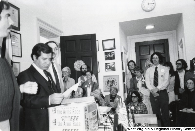 Congressman Nick Rahall II opening a package in the Citizens Lobby while a group of unidentified people watch.