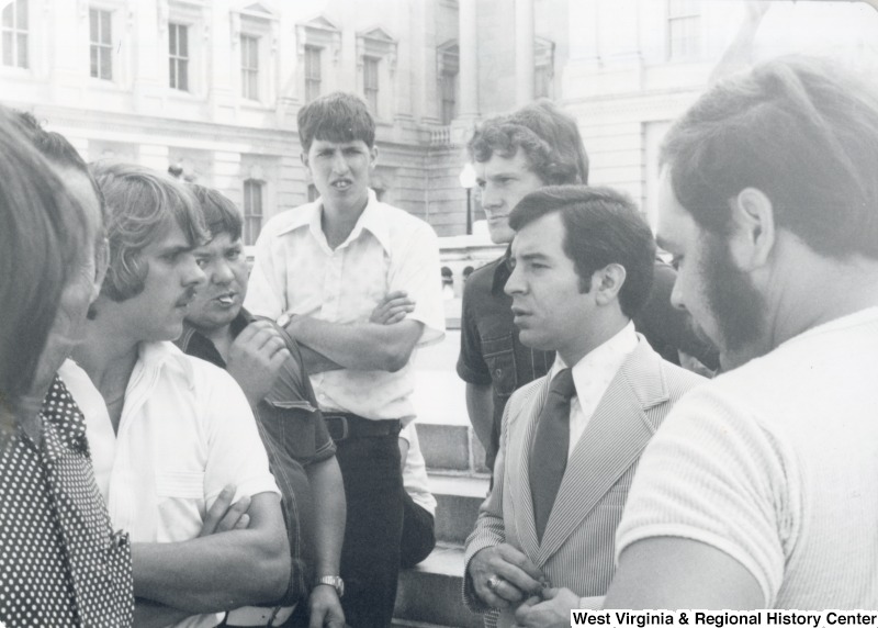 Congressman Nick Rahall II (second from the right) speaking to an unidentified group of men.