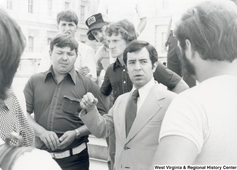 Congressman Nick Rahall II (second from the right) speaking to an unidentified group of men.