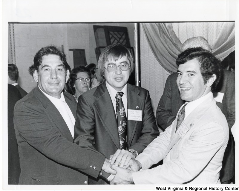 Congressman Nick Rahall II (first on the right) with two unidentified men at the Democratic State 1976 Convention. The three men have their hands stacked together.