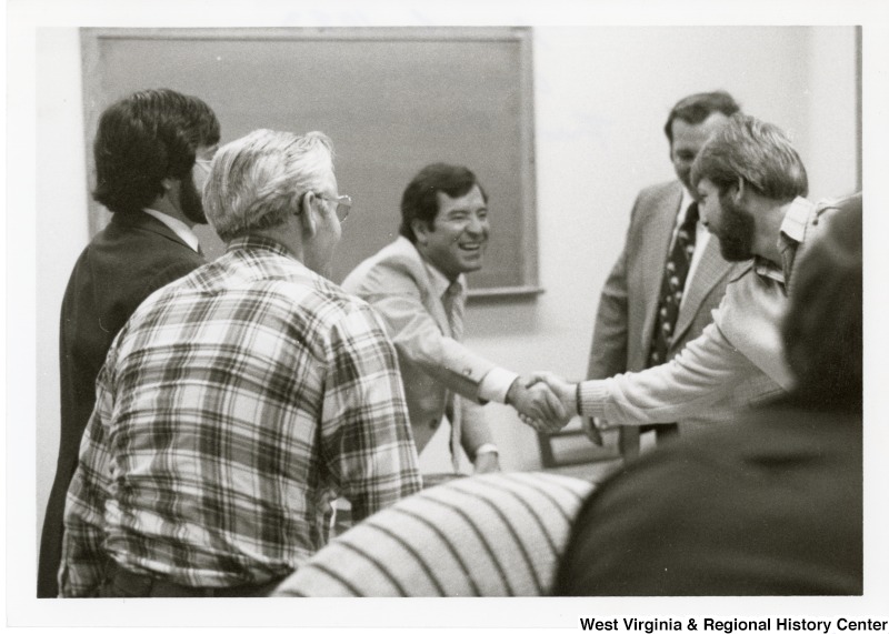 Congressman Nick Rahall II shaking the hand of an unidentified man in the Trade Union Internship Program. Five other unidentified people are standing around them.