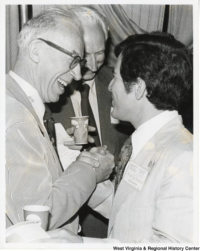 Congressman Nick Rahall II shaking the hand of Congressman Ken Hechler at the 1976 Democratic State Convention. An unidentified man is standing between them.