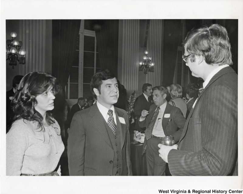 Jane Bone and Congressman Nick Rahall II speaking to an unidentified man at the West Virginia State Society reception in the Cannon Building.