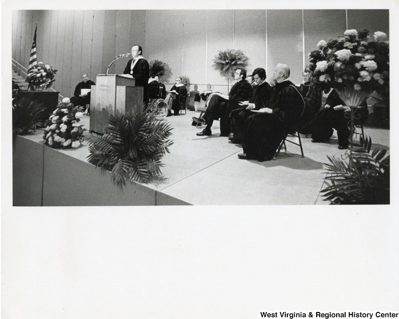 From left to right: Senator Jennings Randolph; speaking at the podium is President of Marshall University Bob Hayes; seated is Governor Jay Rockefeller; Congressman Nick Rahall II; and Congressman Arch Moore Jr. participating in the 1985 Marshall University Commencement program.