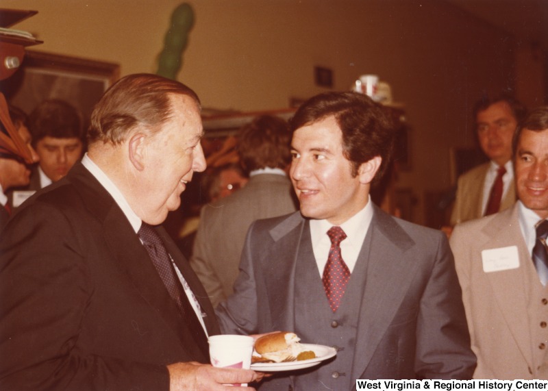 Senator Jennings Randolph (left) speaking to Congressman Nick Rahall II (center) at Rahall's 30th birthday fundraising party. An unidentified man is standing to the right of Rahall.