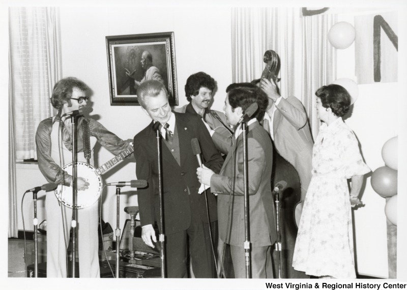 Senator Robert C. Byrd (left) and Congressman Nick Rahall II (right) speaking at Rahall's 30th birthday fundraising party. A unidentified band is standing behind them waiting to play.