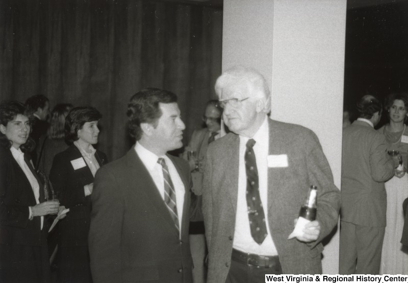 Congressman Nick Rahall II speaking to an unidentified man at one of his birthday parties.