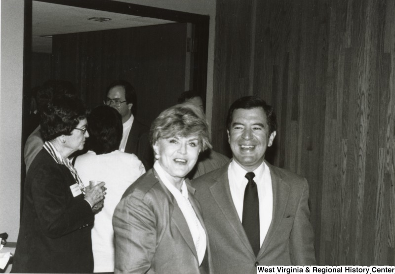 Congressman Nick Rahall II with an unidentified woman at his birthday party.  Behind them are five unidentified people standing in a doorway.