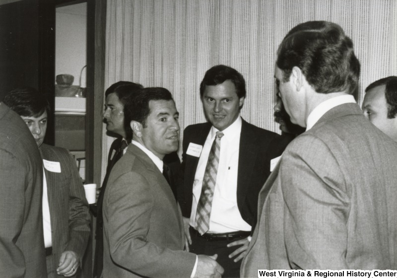 Congressman Nick Rahall II (center) speaking to six unidentified men at his birthday party.
