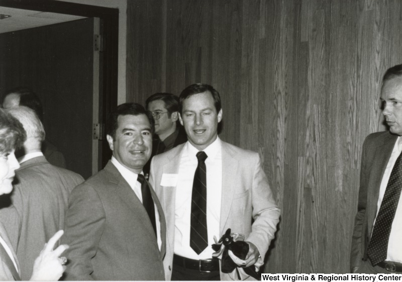 Congressman Nick Rahall II (left) with an unidentified man at his birthday party. There are five unidentified people in the background.