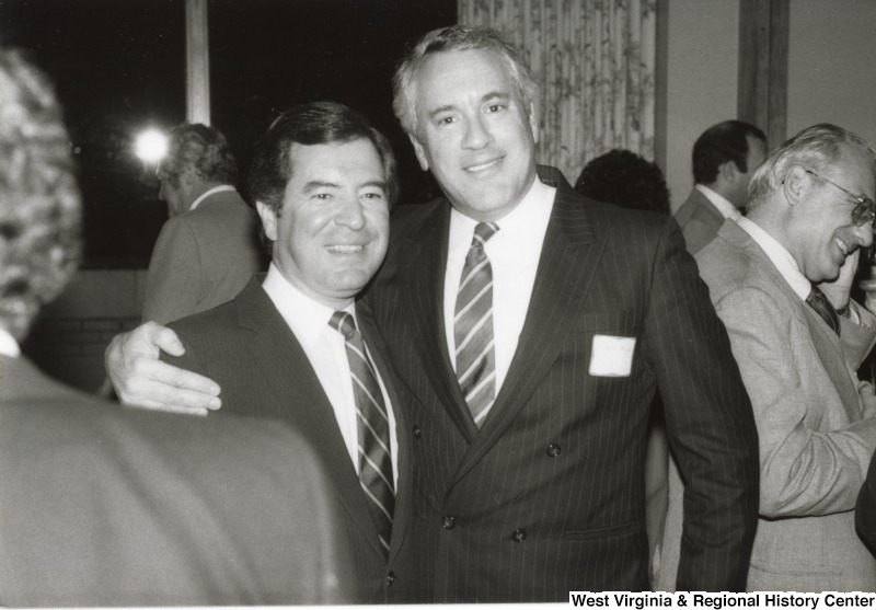 Congressman Nick Rahall II (left) with an unidentified man at his birthday party. The man has his arm around Rahall.