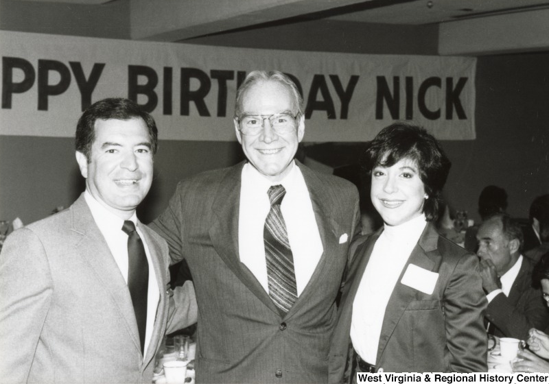 Congressman Nick Rahall II, Congressman Jim Wright, and an unidentified woman at Congressman Rahall's birthday party. A banner in the background reads "Happy Birthday Nick.'