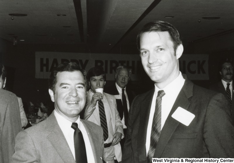 Congressman Nick Rahall II (left) with an unidentified man at his birthday party. Two unidentified man can be seen in the background between them.
