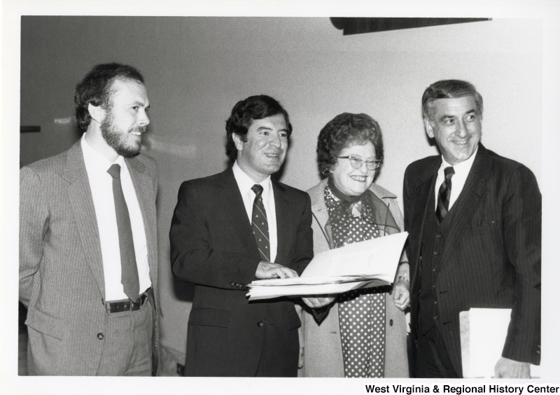 Congressman Nick Rahall II (second from the left) with two unidentified men and one woman. Congressman Rahall is holding a book open.
