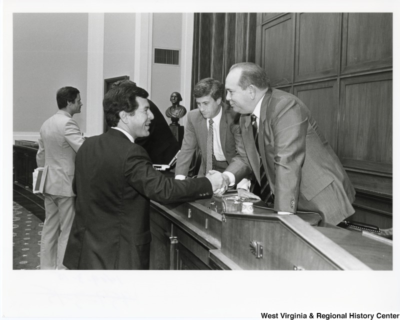 Congressman Nick Rahall II (left) shaking the hand of an unidentified man. Two other unidentified men can be seen standing behind them.